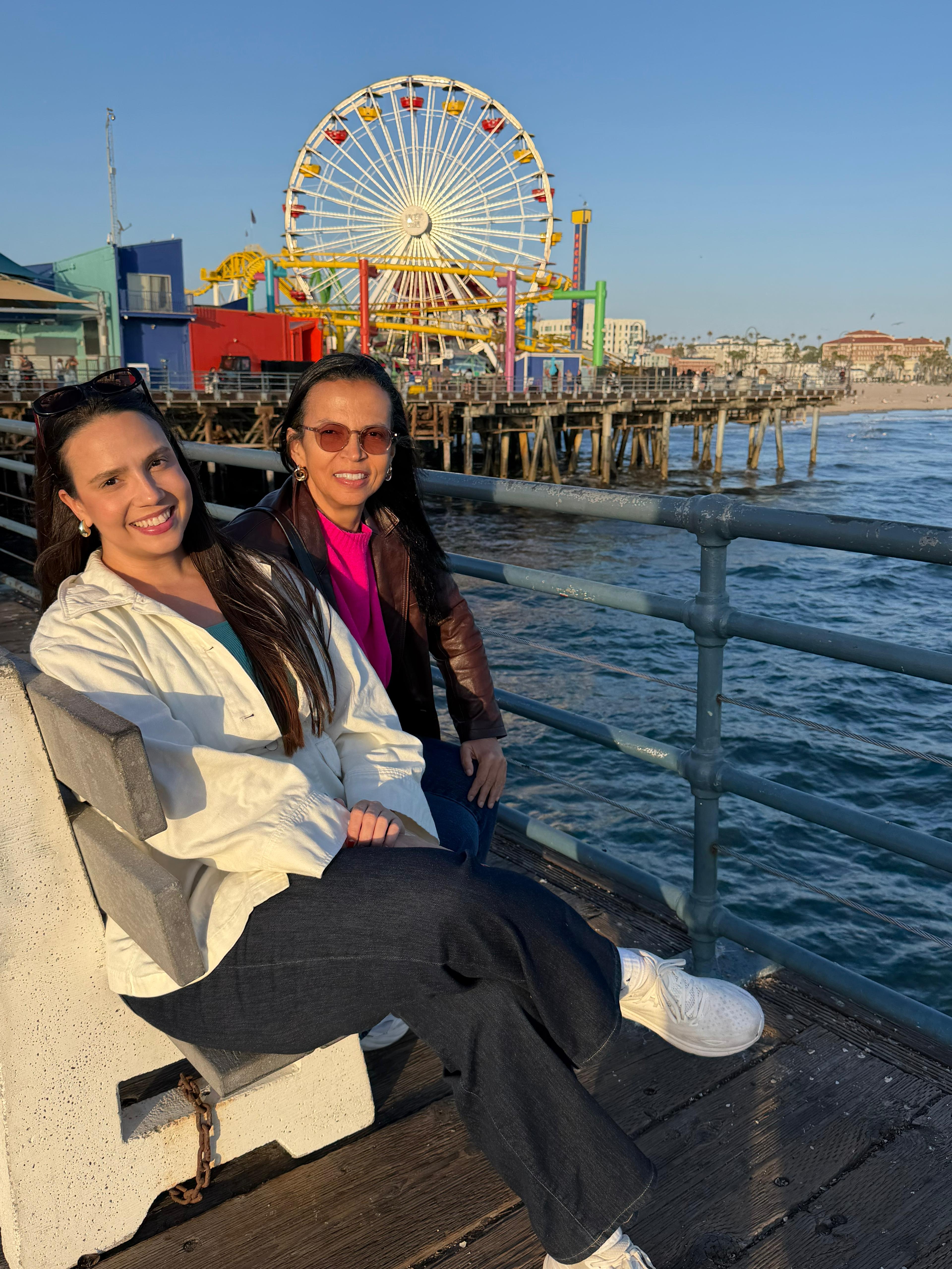 Duas amigas sentadas com a roda gigante do píer ao fundo